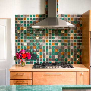 Multicolored tile backsplash in a kitchen with modern cabinets and a jade green countertop 