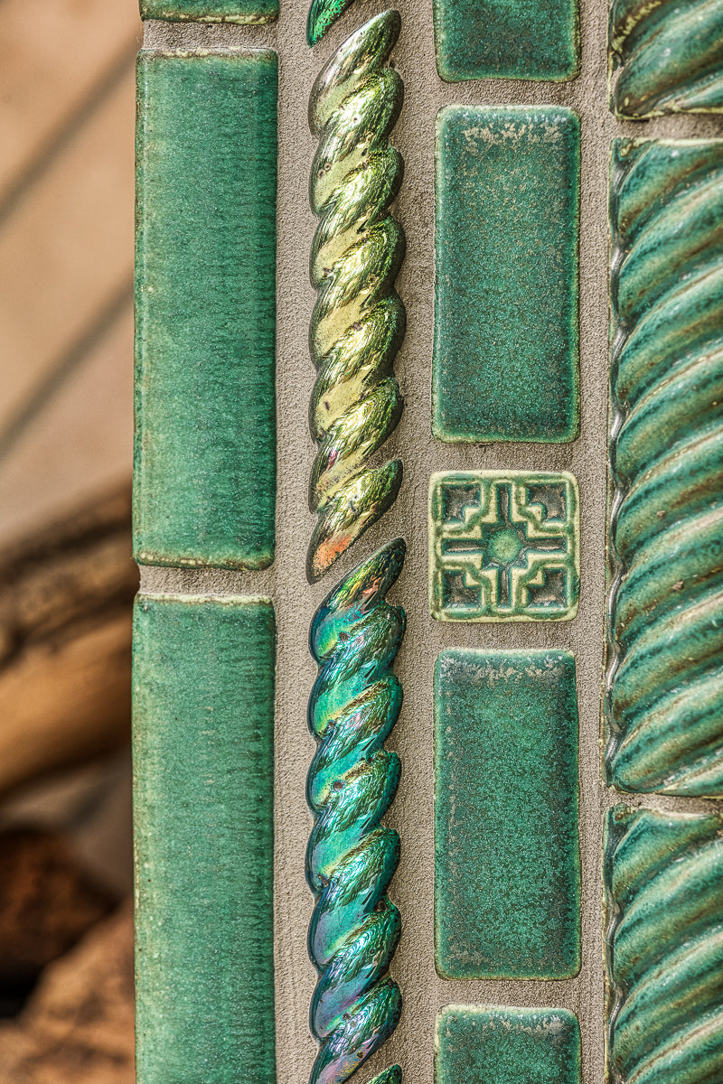 Detail shot of custom-cut rope motif tiles in Aurora Iridescent and Pewabic Green glazes. There is also a traditional Pewabic accent tile featured at the photo's center. 