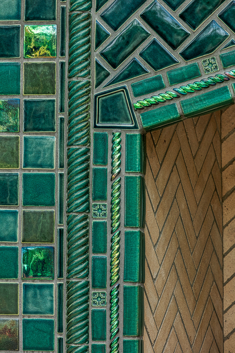 Detail shot of the fireplace that includes Iridescent and varying blue/green field tiles along with custom-cut tiles crafted specifically for this installation.