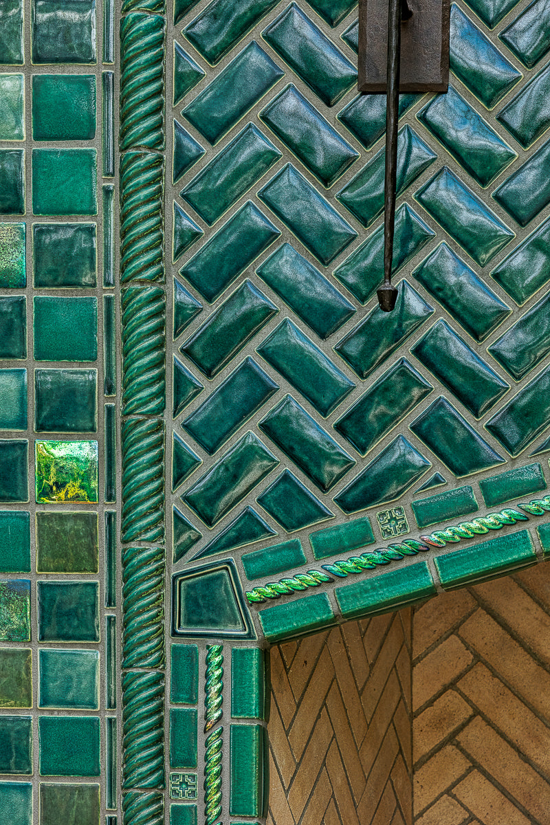 Detail shot of the fireplace that includes Iridescent and varying blue/green field tiles along with custom-cut tiles crafted specifically for this installation.
