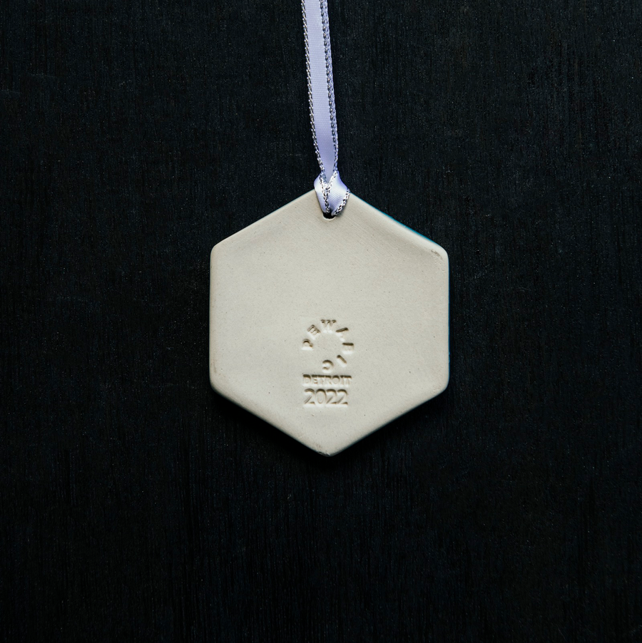 The back of the Snowflake Ornament with a Pewabic logo, the date of 2022, and "Detroit" stamped into the clay near the lower center of the piece.