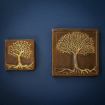 The two Tree of Life tiles feature the same tree design. There is no earth below the tree, only roots that stretch to the bottom corners of the tile. The branches reach out from the thick trunk and are covered in small leaves.