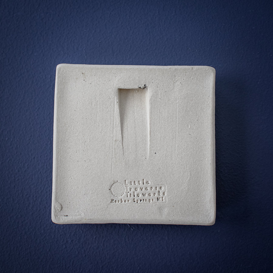The back of the tile has a notch for easy hanging. There is a logo stamp that says "Little Traverse Tileworks Harbor Springs, Michigan".