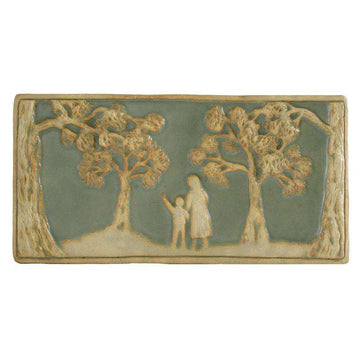 This landscape oriented rectangular tile features a woman holding hands with a child with their backs toward the viewer. The child is pointing up at the surrounding trees as they walk through a sparse forest. The trees and figures are scraped giving them a creamy white color while the background is pale green. 